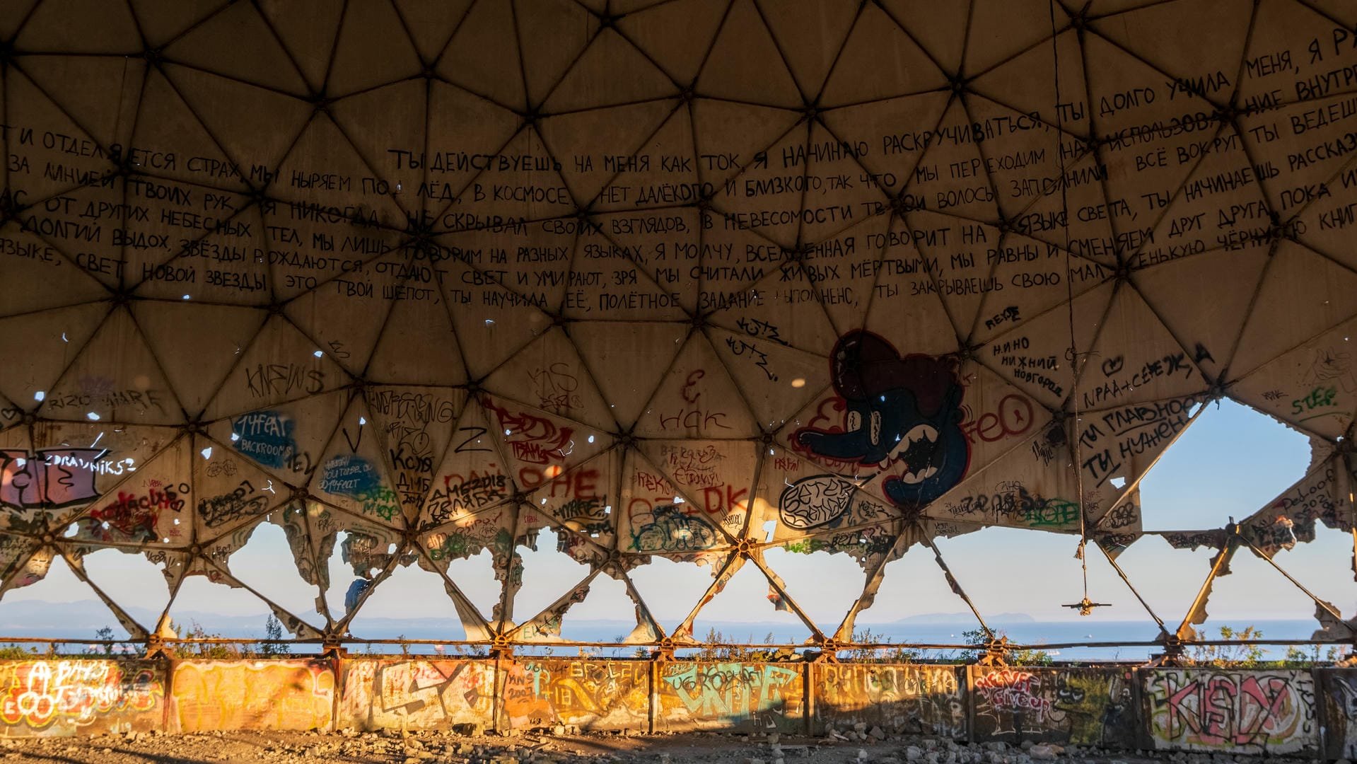 The interior of the domed structure, with walls covered in graffiti and text, and a partially damaged ceiling structure.