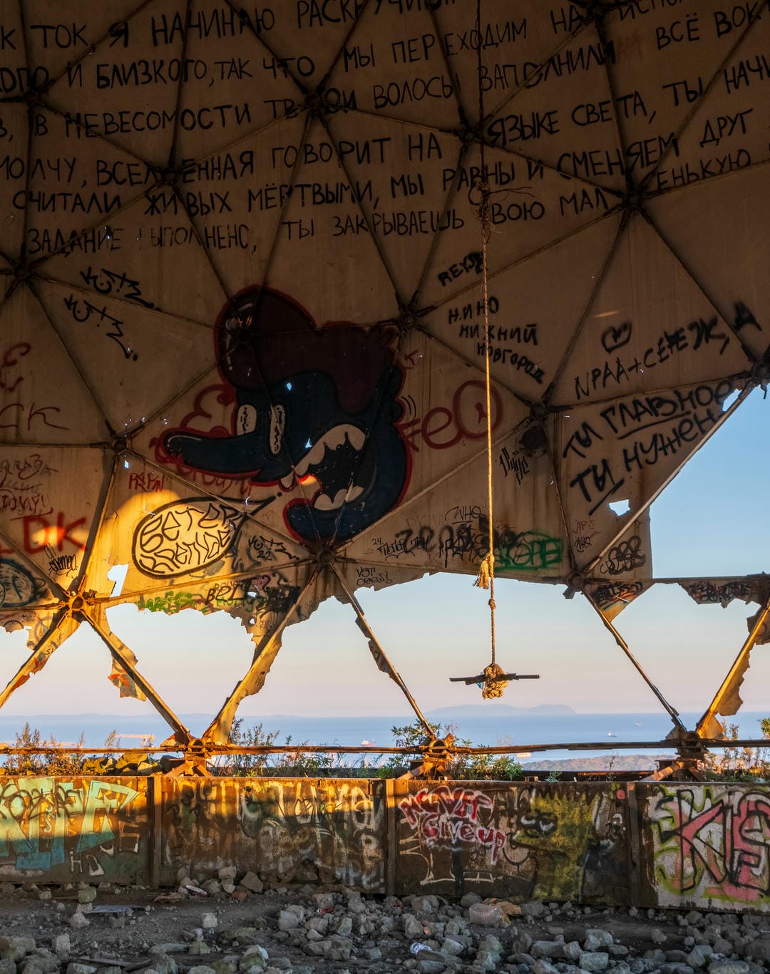 A close-up of the interior of the domed structure, featuring a blue cartoon pattern in the center of the ceiling, surrounded by various graffiti.