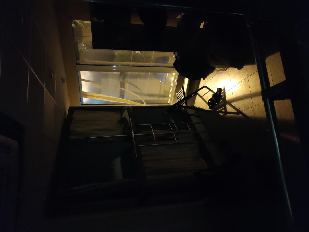 A dimly lit room with faint light coming through the window, showing a bed and other items inside.