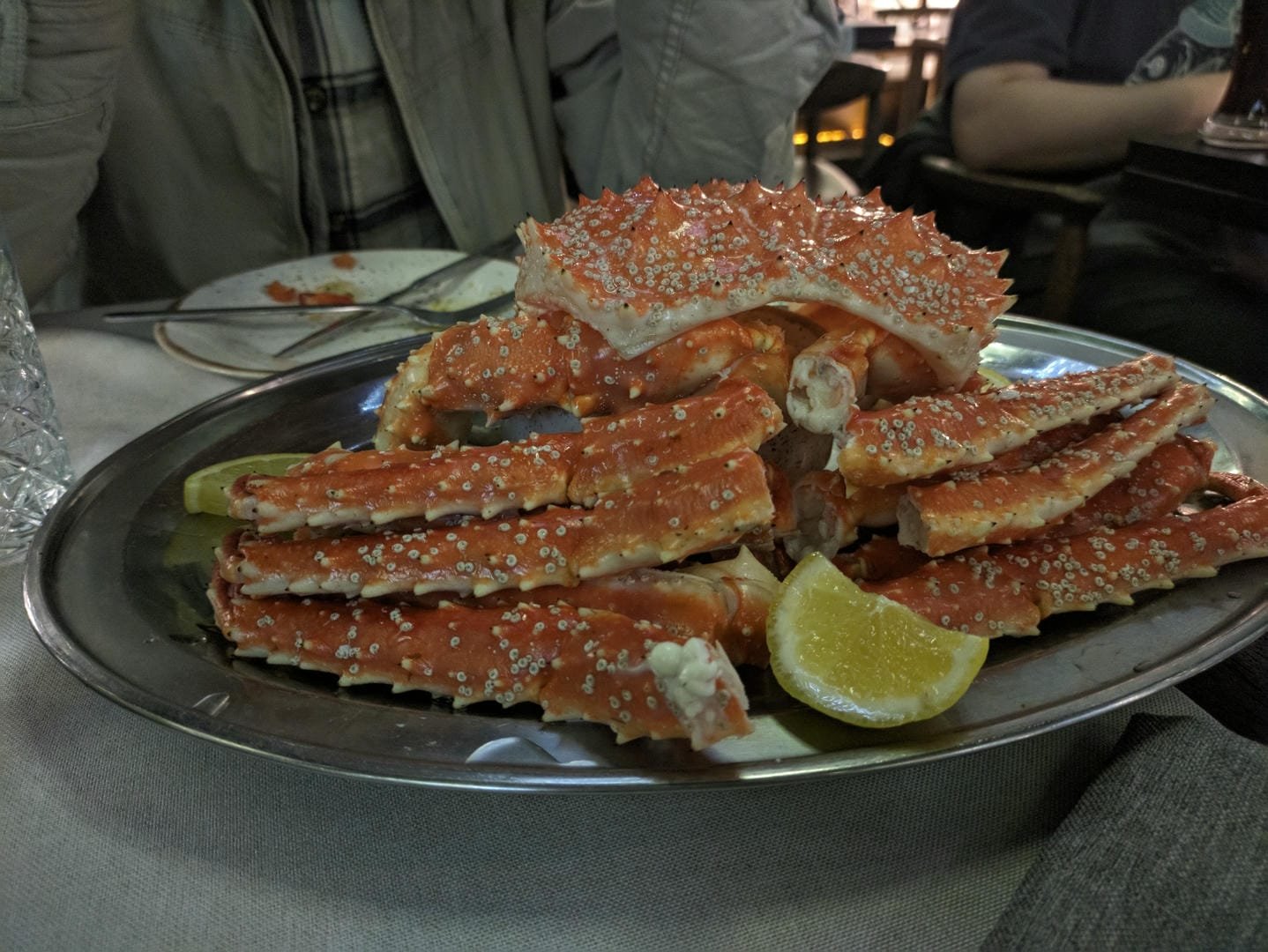 A platter of king crab legs served on a silver plate, with a lemon wedge on the side.
