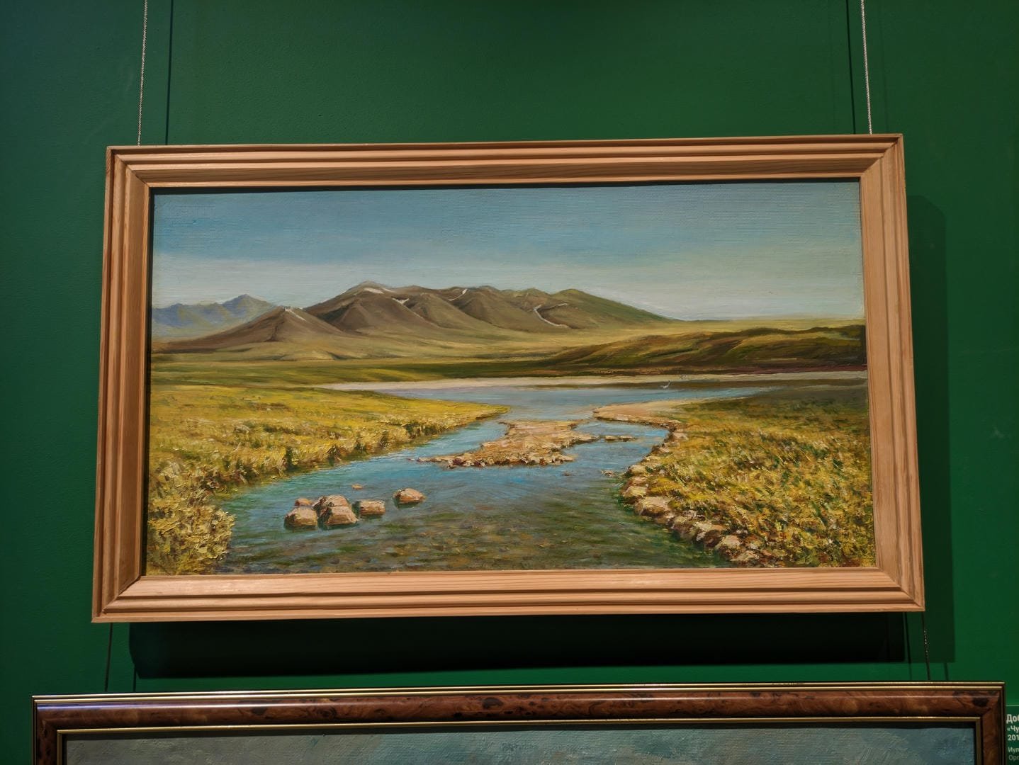 A painting depicting a serene natural landscape, featuring a winding stream in the foreground flanked by lush meadows, under rolling mountains in the background.