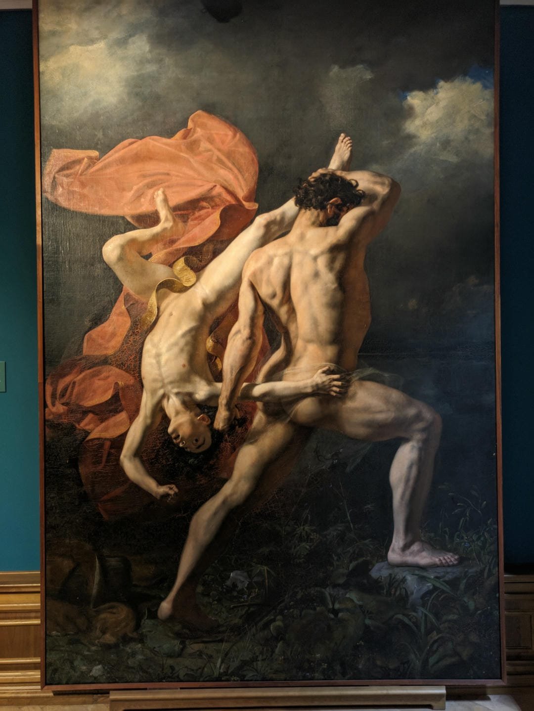 A painting depicting a muscular man wrestling with another fallen man, with flowing red cloth in the background.